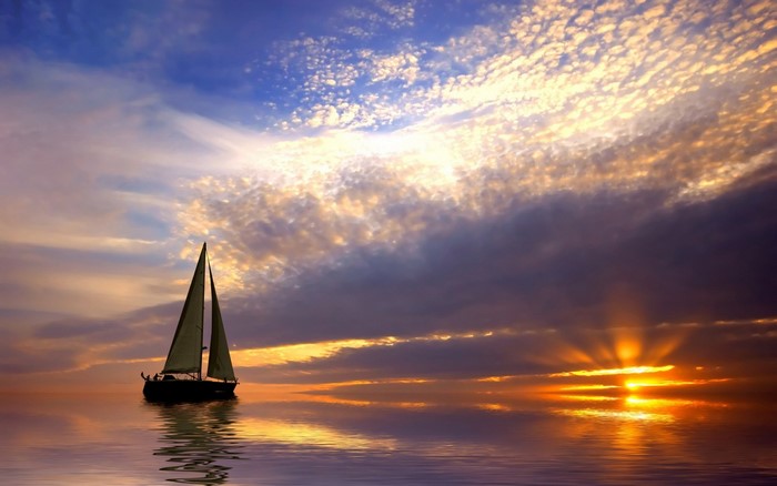 Sailboat on the sea at sunset with dramatic clouds
