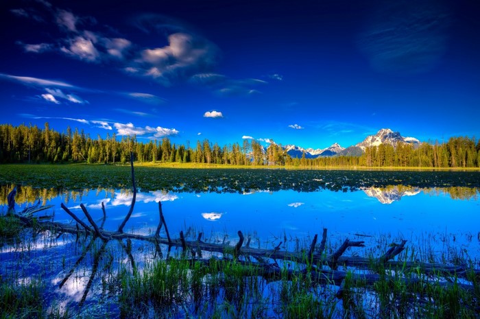 Lake reflection of mountains and forest under blue sky
