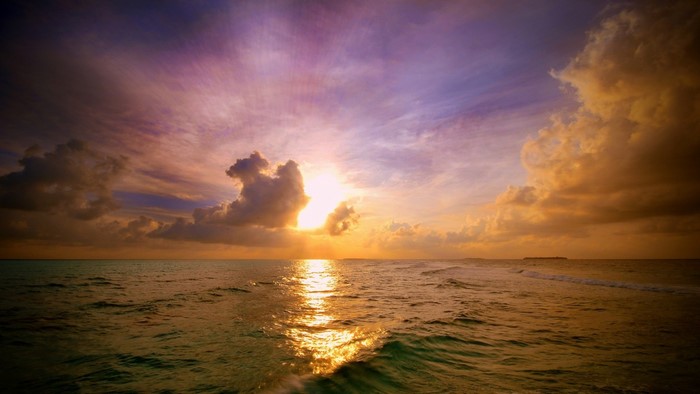 Sunset over the ocean with colorful clouds and waves