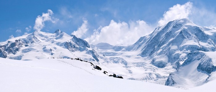 Snow-covered mountains under a blue sky with clouds