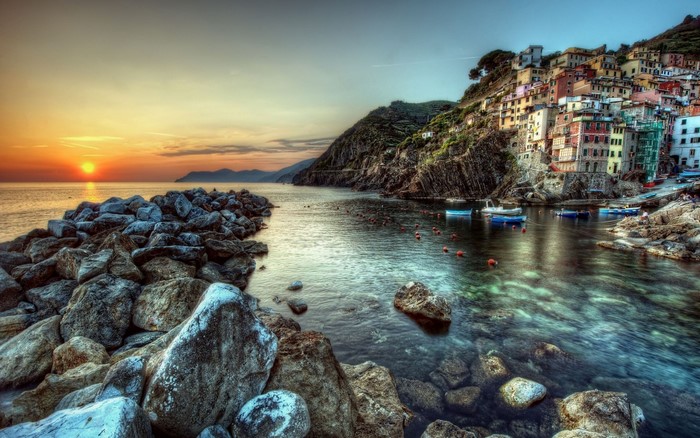 Sunset over Riomaggiore, Italy coast with boats and rocks