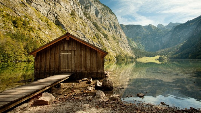 Wooden boathouse on a clear lake with mountains