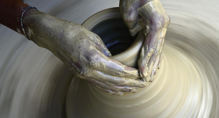 Hands shaping clay on a pottery wheel