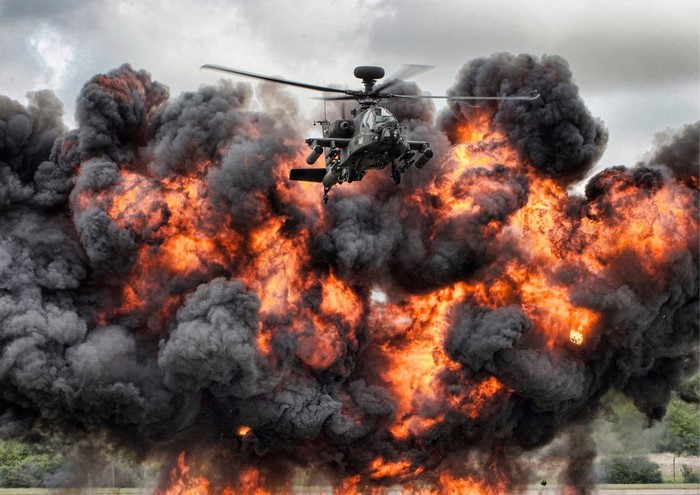 Apache helicopter flying through a large explosion