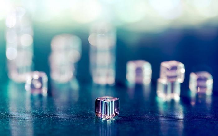 Clear cubes on a dark reflective surface with bokeh background