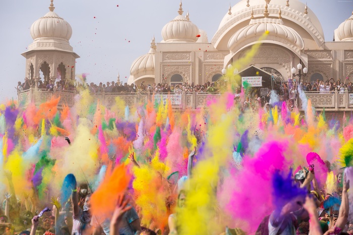 People celebrating Holi with colored powder in front of a temple