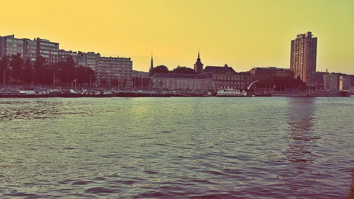 Cityscape with buildings and boats on a river at sunset