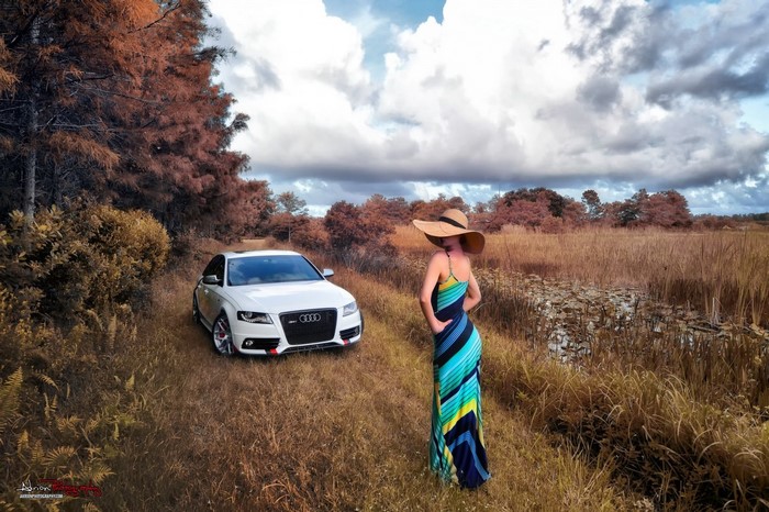 Woman in hat and dress next to white Audi car