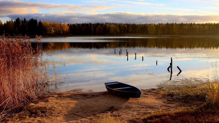Boat on the shore of a lake during autumn sunset