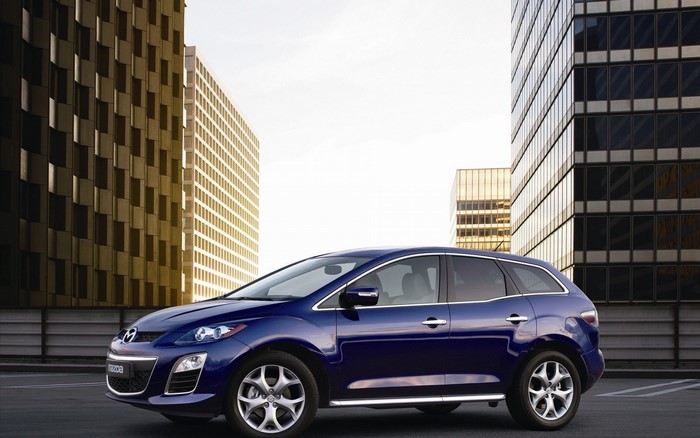 Blue Mazda CX-7 parked in front of modern buildings
