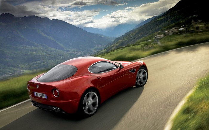 Red Alfa Romeo 8C Competizione driving on mountain road
