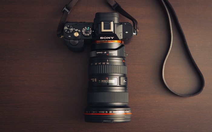 Sony camera with Canon zoom lens on wooden surface