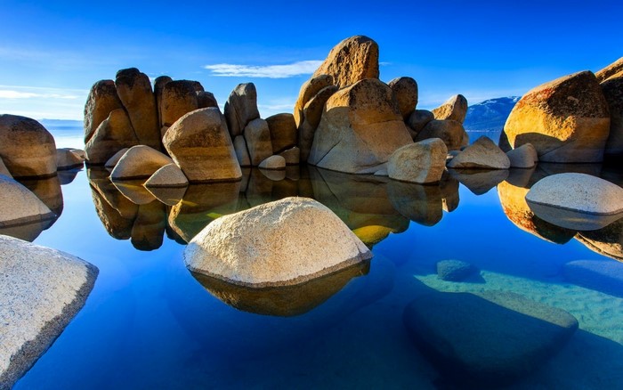 Rocks in a calm blue lake with reflections
