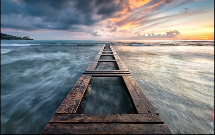 Wooden pier extending into the sea at sunset