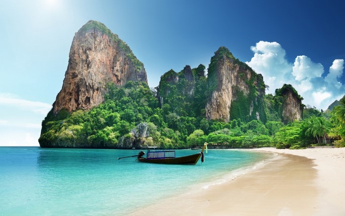 Longtail boat on a tropical beach with limestone cliffs