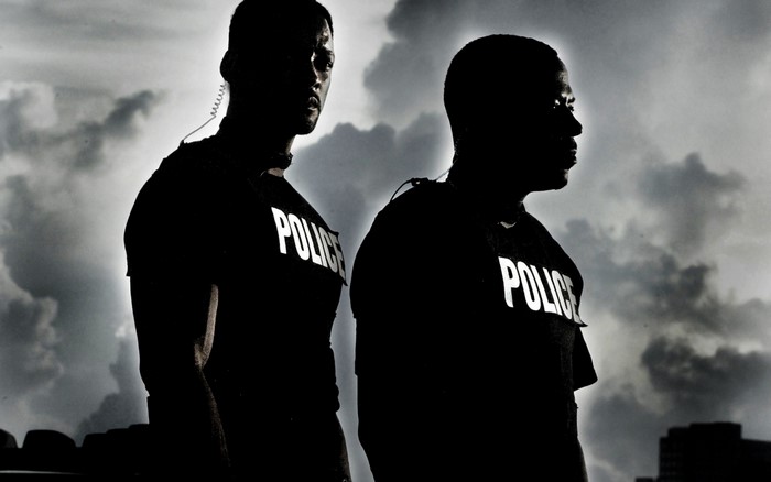 Two police officers in silhouette against a cloudy sky