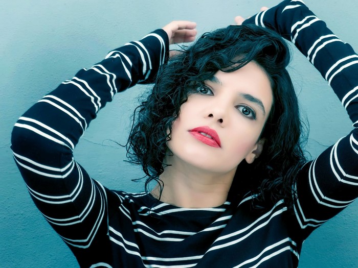 Woman with curly black hair and red lipstick