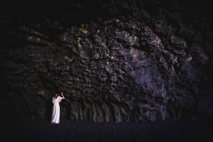 Woman in white dress in a dark cave with rock formations