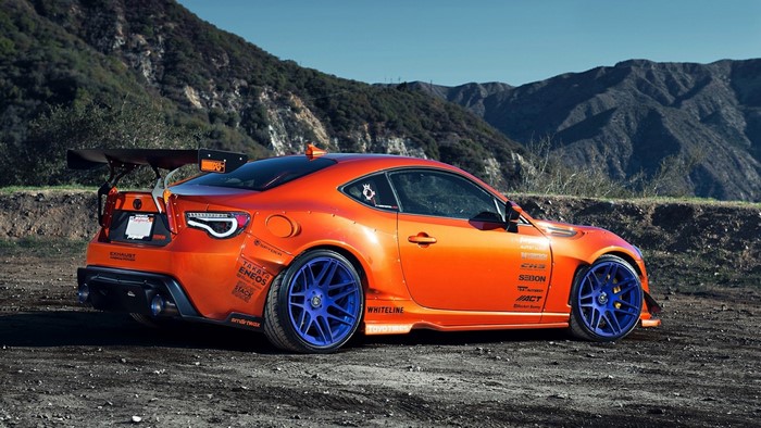 Orange Toyota 86 with large rear wing and blue wheels