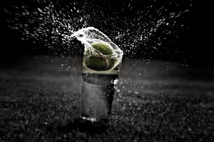 Tennis ball splashing in water in a glass