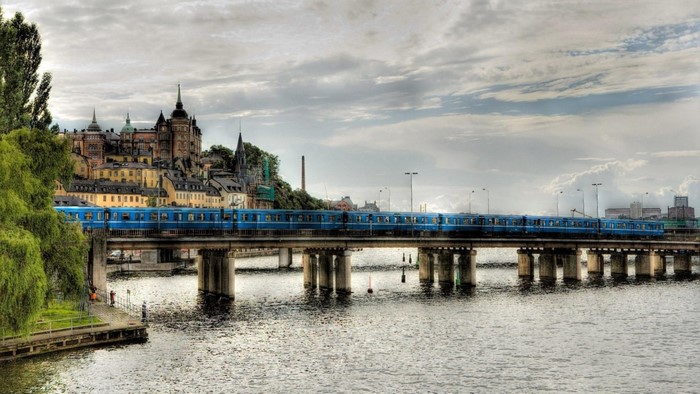 Blue train crossing a bridge over a river in Stockholm, Sweden
