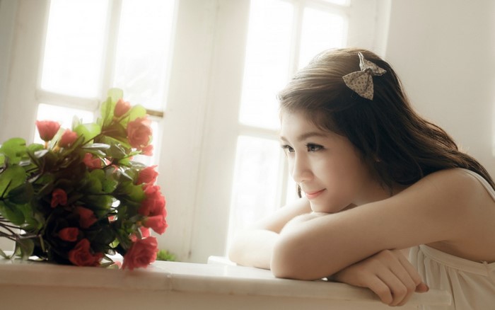 Young Asian woman with flowers by the window