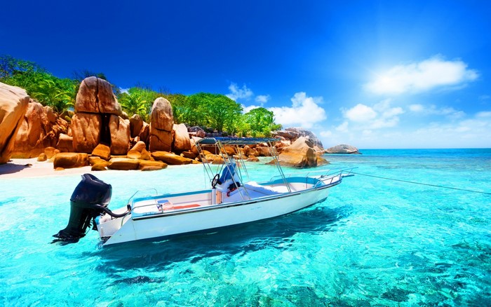 Boat anchored in turquoise water near rocky island beach