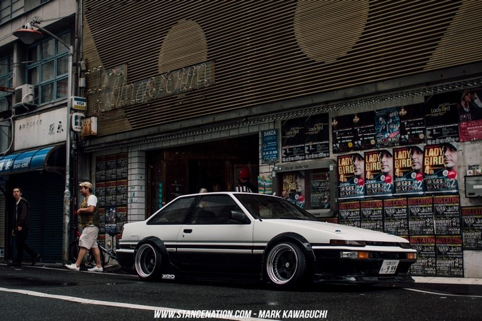 White and black Toyota AE86 parked on a street in Japan