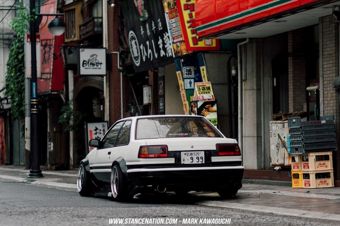 White Toyota AE86 sports car parked on a street in Japan