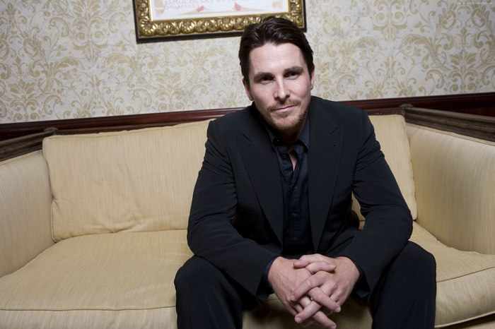 Christian Bale sitting on a couch