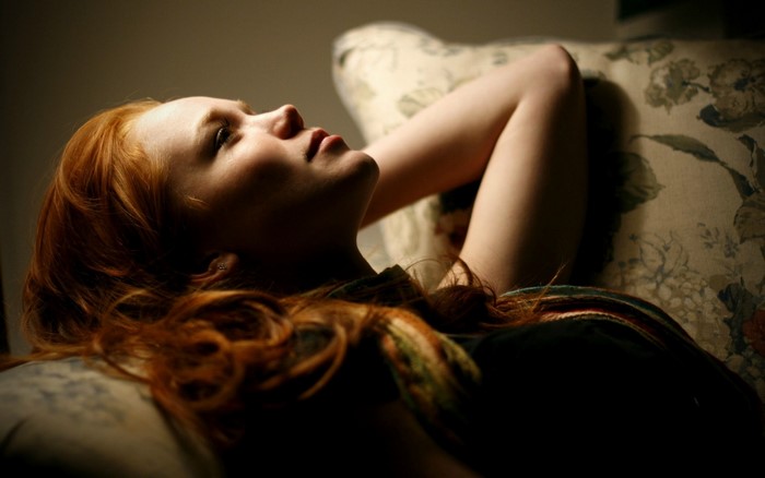 Woman with red hair lying on a couch
