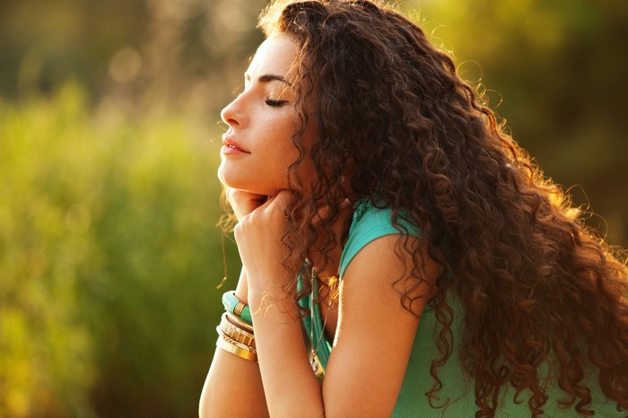 Woman with curly brown hair in sunlight