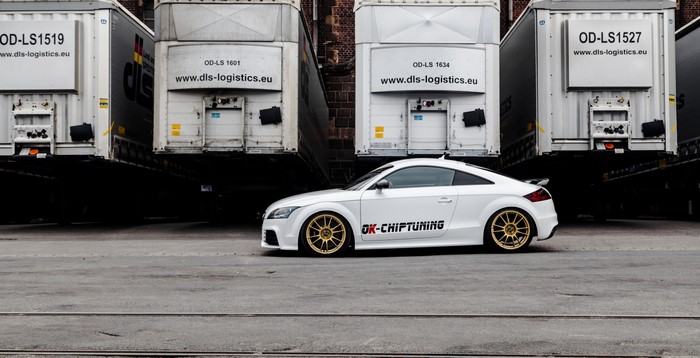 White Audi TT with OK-CHIPTUNING logo parked near trucks