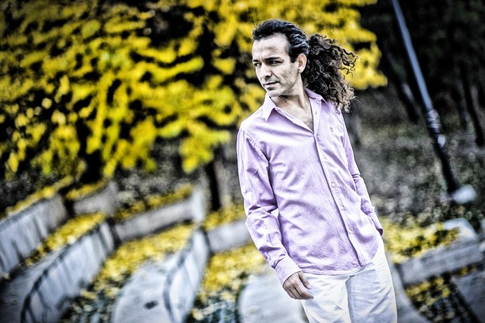 Man with long curly hair in a pink shirt