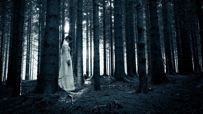 Woman in white dress in a dark forest