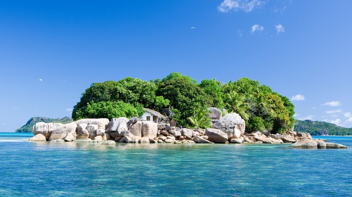 Tropical island with a small house and clear blue water