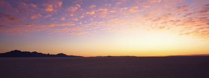 Sunset over a vast desert landscape with mountains