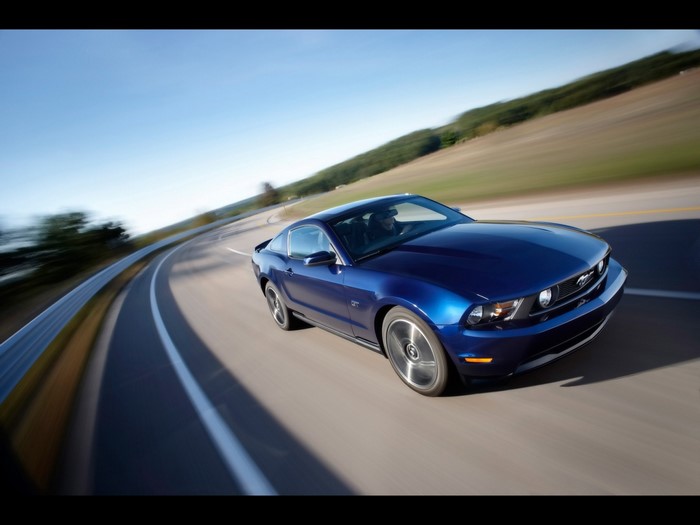 Blue Ford Mustang GT driving on a winding road