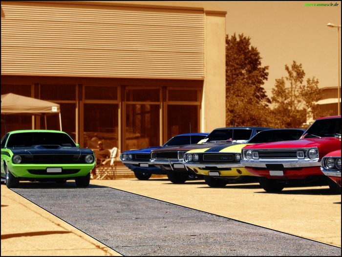 Several classic American muscle cars parked in a lot