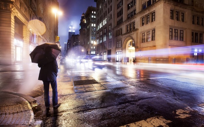 Person with umbrella on a wet city street at night
