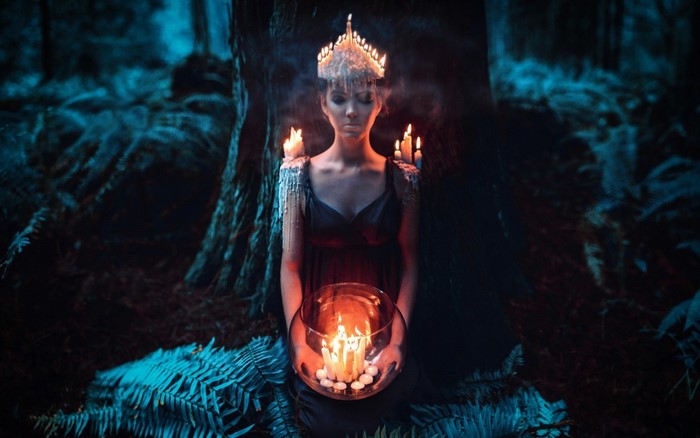 Woman with candles in a dark forest