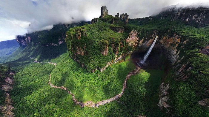 Aerial view of a lush green mountain range with a waterfall