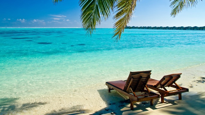 Tropical beach with lounge chairs and ocean bungalows