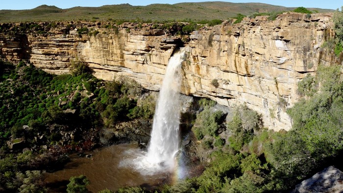 Waterfall cascading over a rocky cliff face with vegetation
