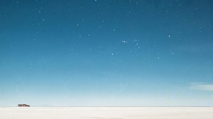 A lone building on a salt flat under a starry sky