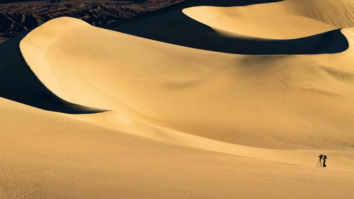 Photographer with tripod on sand dunes