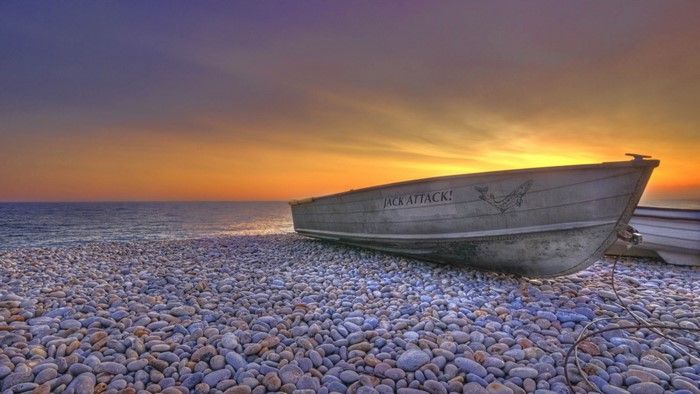 Boat on a pebble beach at sunset