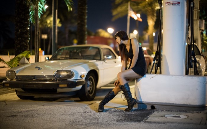 Woman in black dress and boots by Jaguar XJS