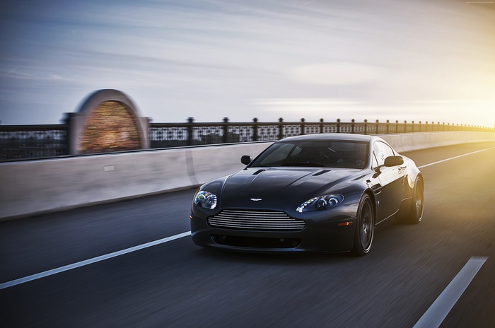 Black Aston Martin Vantage driving on a bridge