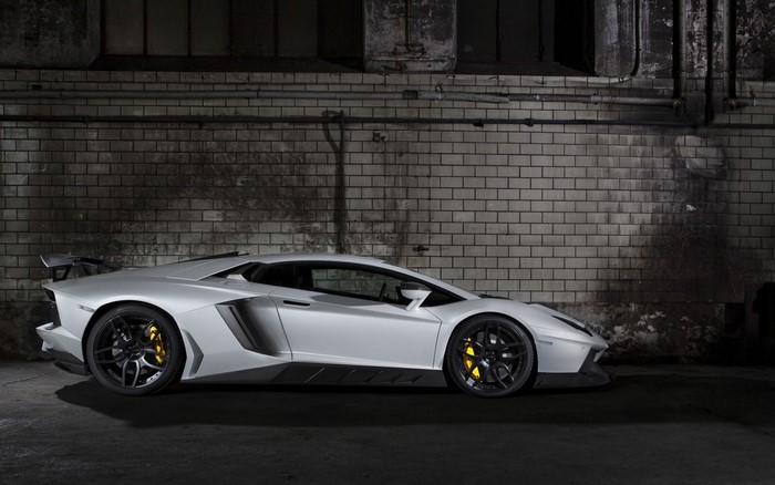White Lamborghini Aventador parked against a brick wall